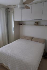 a bedroom with a white bed with a ceiling at Apartamento Familia Granja Viana in Carapicuíba