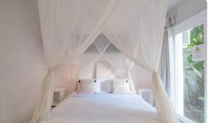 a bedroom with a white bed with a window at Steps to Canggu Beach Six Bedrooms, Five Baths in Denpasar