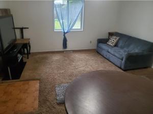 a living room with a blue couch and a table at Hot Tub with King Bed in Anchorage