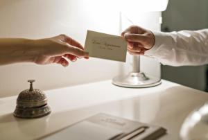 two people holding up a piece of paper on a counter at Louis Appartements Galata in Istanbul