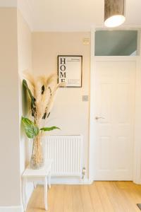 a vase with feathers in it sitting on a table next to a door at Modern 2-Bedroom London Base - 15 mins to Central London - Next to East Croydon Station - Sleeps 5 in Croydon +12 photos