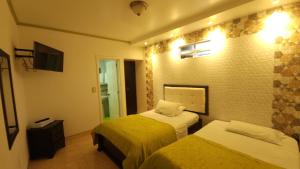 a hotel room with two beds and a television at Paraíso Dorado - Hotel Express in Aguadas