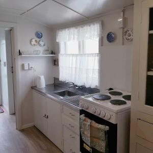 a kitchen with a stove and a sink and a window at Little Rose Cottage in Rotherham