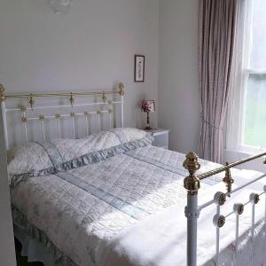 a bedroom with a white bed and a window at Little Rose Cottage in Rotherham