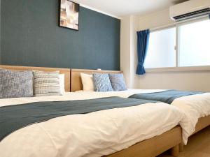 two beds sitting next to each other in a bedroom at Liaison Apartment Shinsaibashi in Osaka