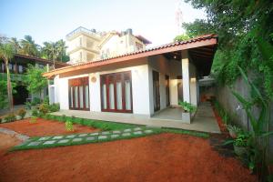 a small white house with a red dirt yard at Hiriketiya Nanda Homestay in Dickwella