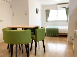 a room with a table and green chairs and a bed at Liaison Apartment Shinsaibashi in Osaka