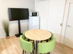 a kitchen with a wooden table and green chairs at Liaison Apartment Shinsaibashi in Osaka