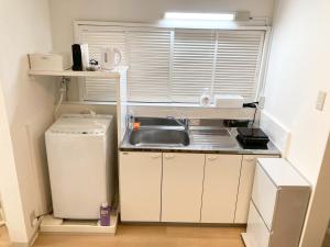 a small kitchen with a sink and a refrigerator at Liaison Apartment Shinsaibashi in Osaka