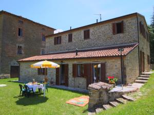 un patio con mesa y sombrilla frente a un edificio en Country House Getaway in Apecchio, en Apecchio