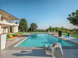 a swimming pool with chairs and a table in front of a house at Tranquil Escape in Tavullia in Tavullia