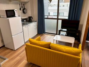 a living room with a yellow couch and a kitchen at お宿あびこシルバーハイツ in Osaka