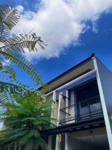 a white building with a balcony and a palm tree at The Olla Villa in Yogyakarta