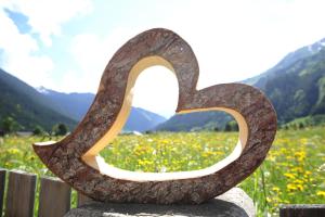 a sculpture of a heart sitting on a rock in a field at Luxury Chalets Wiesenruh in Bichlbach