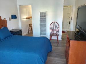 a bedroom with a bed and a chair and a television at Oceana Boutique Hotel in San Clemente