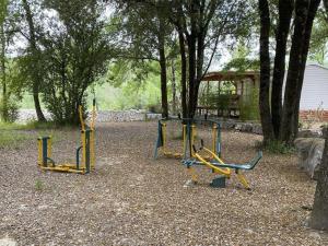 two childrens playground equipment in a park with trees at Mobil home confortable avec terrasse pour 6 personnes - API-1-52-393 in Saint-Maurice-dʼIbie
