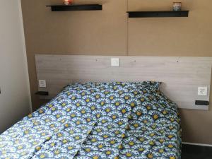 a bed with a blue and yellow bedspread on it at Mobil-home confortable avec terrasse - API-1-52-641 in Le Boulou +19 photos