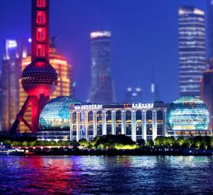a large building with a city in the background at night at Oriental Riverside Bund View Hotel (Shanghai International Convention Center) in Shanghai