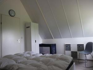 a room with a bed and a chair and a clock at Holiday home near Waterdunen for 6 in Breskens +25 photos