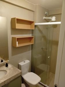 a bathroom with a toilet and a glass shower at Flat08 Tamandaré Carneiros in Tamandaré