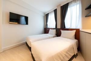 two beds in a hotel room with a tv at Hmlet Essentials Novena in Singapore