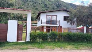 a white house with a fence and a mountain at Centro recreativo y Casa de campo in Orcotuna