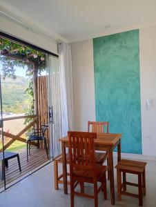 a dining room with a table and chairs and a balcony at Chalés Vista dos Carvalhos in Capitólio
