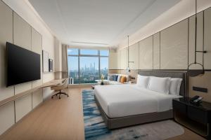 ein Hotelzimmer mit einem Bett und einem Flachbildfernseher in der Unterkunft Crowne Plaza Guangzhou Window of Canton-Free Shuttle Bus Available during Canton Fair Period in Guangzhou
