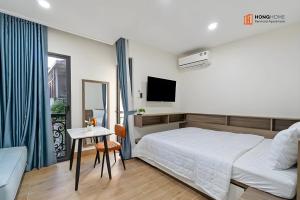a bedroom with a bed and a table and a tv at HongHome Nguyễn Cửu Vân in Ho Chi Minh City