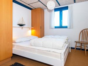 a bedroom with a bed and a window and a chair at 5 star holiday home in Ringkøbing in Klegod