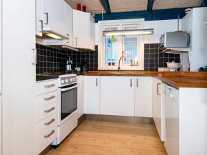 a kitchen with white cabinets and a sink at 5 star holiday home in Ringkøbing in Klegod