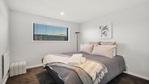 ein weißes Schlafzimmer mit einem Bett und einem Fenster in der Unterkunft Harper on Hadley - Cromwell Holiday Home in Queenstown