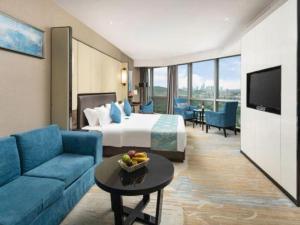 a hotel room with a bed and a couch and a television at Nanning Champs Elysees Hotel in Nanning