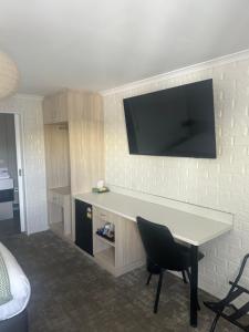 a room with a desk with a television on a wall at The Shamrock Hotel in Toowoomba