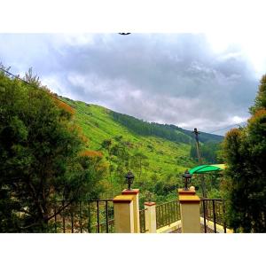a house with a fence and an umbrella on a hill at Greens Vagamon in Vagamon