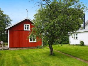 a red barn and a tree in a yard at 4 person holiday home in Götene in Götene