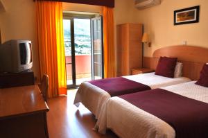 una camera d'albergo con due letti e una televisione di Hotel Solneve a Covilhã