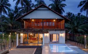 a house with a pool in front of it at Bougainvillea Beach Home - Guruvayur - Chavakkad in Manattala