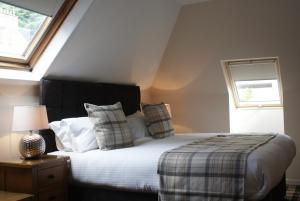 1 dormitorio con cama con almohadas y ventana en The Glen Mhor Apartments, en Inverness