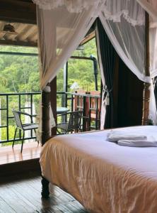 una camera da letto con letto a baldacchino e balcone di บ้านเอื้องดอยแม่กำปอง a Ban Pok Nai Altre 5 foto