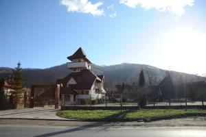 a large building with a fence in front of a mountain at Castelul de Smarald in Pângărăcior