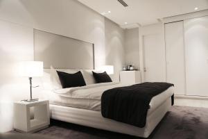 a white bedroom with a large bed and a lamp at Rafa in Riyadh