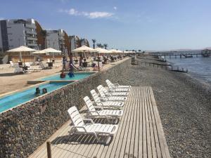 a row of white lounge chairs next to a swimming pool at Paracas Beach Vacation Rentals in Paracas