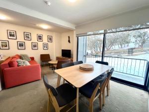 a living room with a table and a red couch at Chalet Apartments - Mt Buller Apartment Rentals in Mount Buller