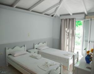 two beds in a white room with a window at Steven in Vasiliki