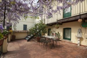 un patio con mesa, sillas y flores púrpuras en Antica Corte, en Busto Arsizio