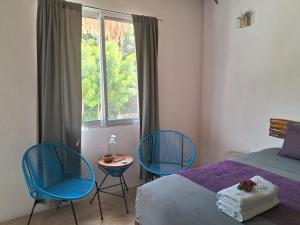 una camera da letto con due sedie, un letto e una finestra di Hotel Posada Mykonos a Bacalar