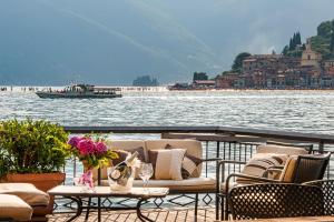 a deck with chairs and tables and a boat on the water at Villa Sofia in Sulzano