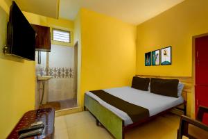 a yellow bedroom with a bed and a television at Hotel O Egmore Metro Station Chennai Formerly Harini Lodge in Chennai