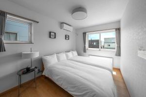 a bedroom with a white bed and two windows at The Vertex in Asahikawa